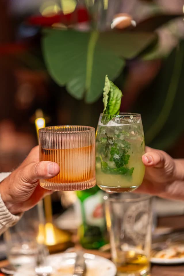 Two guests toasting with cocktails at the table