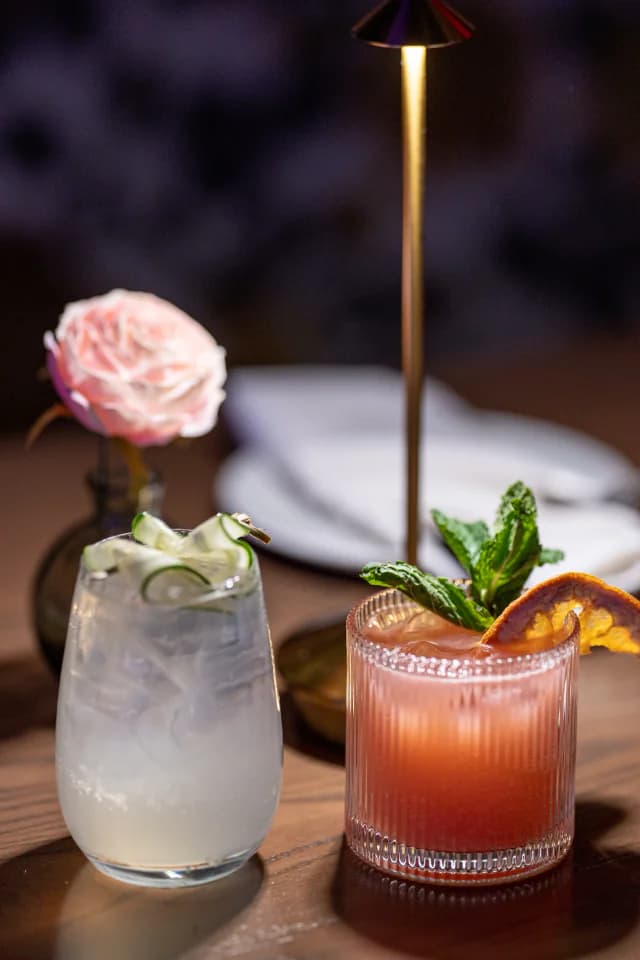 Two cocktails on a table set with a single rose