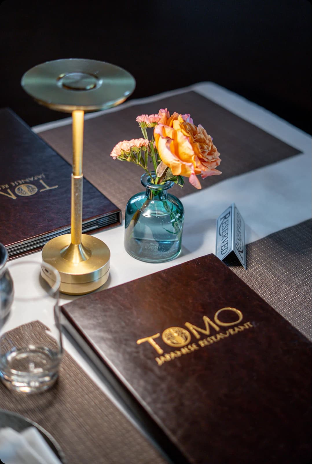 A table set at Tomo Japanese, with the menu and fresh flowers